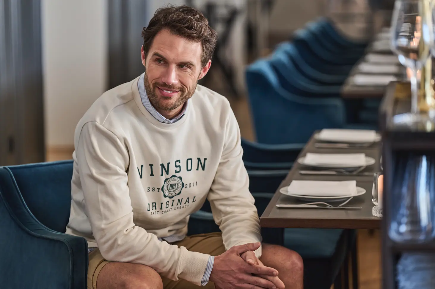 Hombre con sudadera crudo sobre camisa sentado en un restaurante - Dress code casual arreglado VINSON
